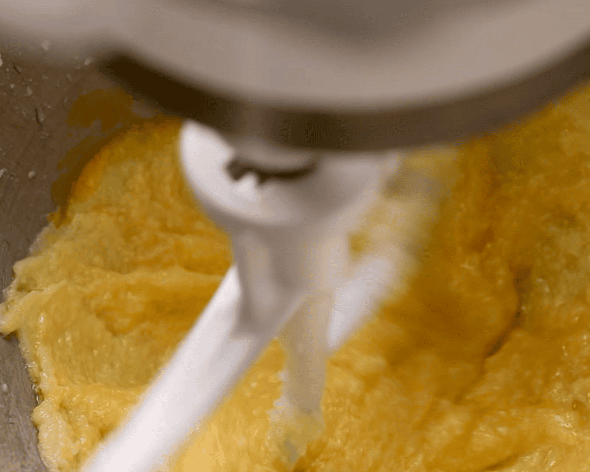 Mixing the sugar mixture with eggs in an electric mixer.