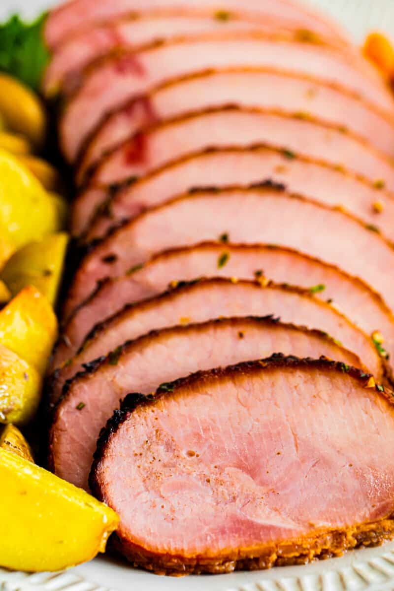 sliced air fryer ham with garlic herb butter on platter