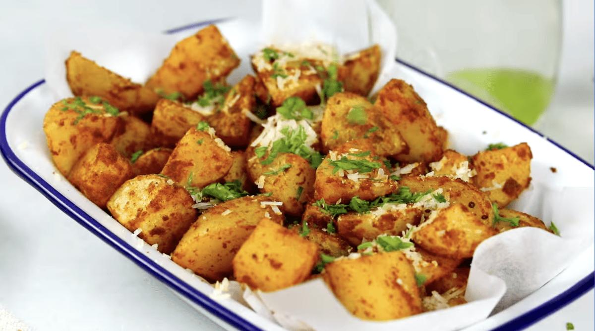 air fryer potatoes topped with cheese and parsley in a white dish.
