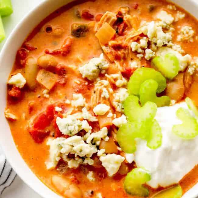 up close buffalo chicken chili garnished with sour cream, blue cheese, and celery