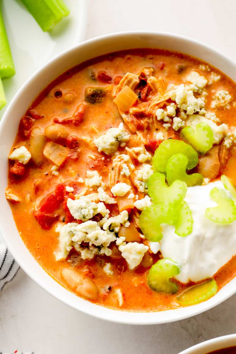 up close buffalo chicken chili garnished with sour cream, blue cheese, and celery