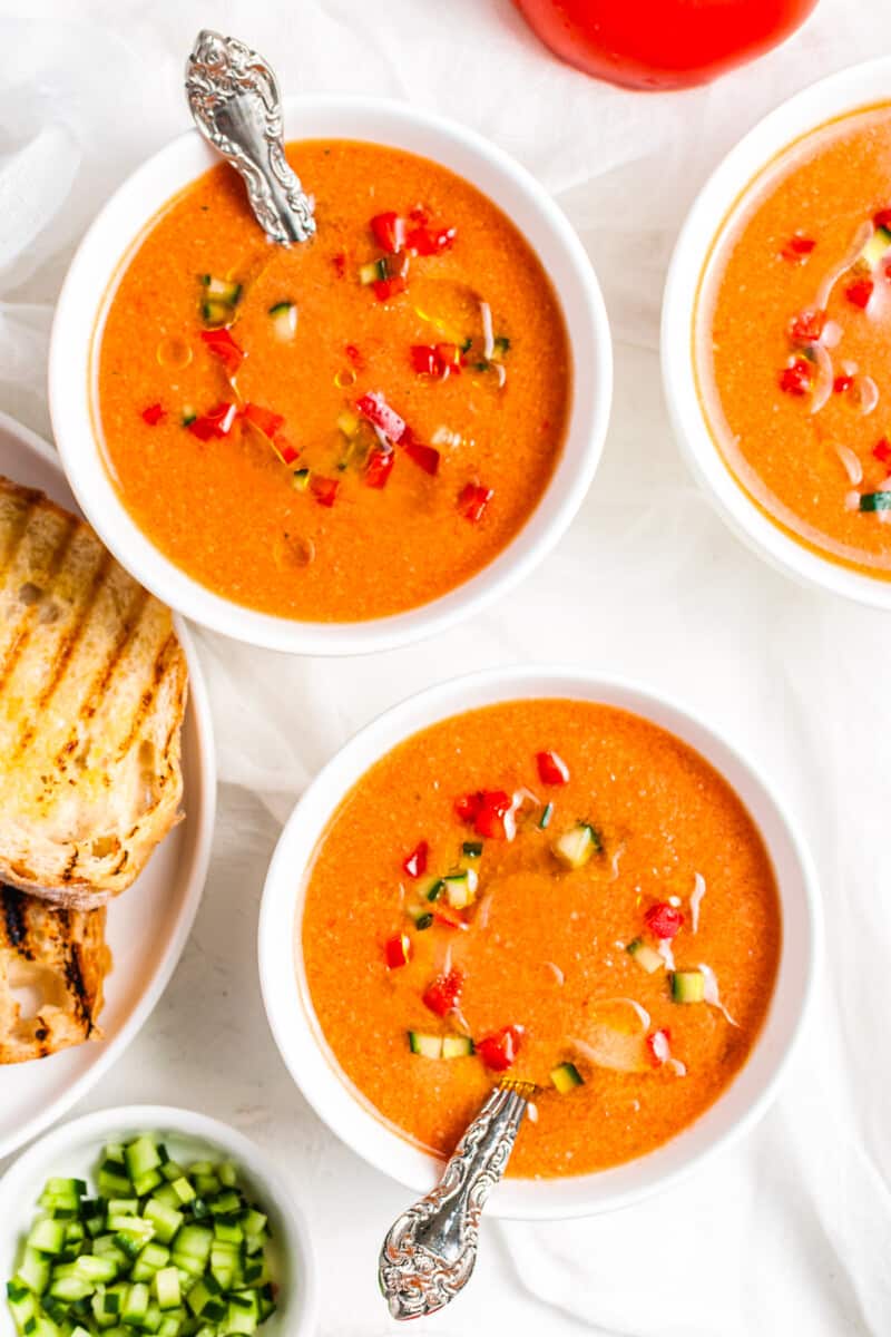 gazpacho in white bowls next to bread
