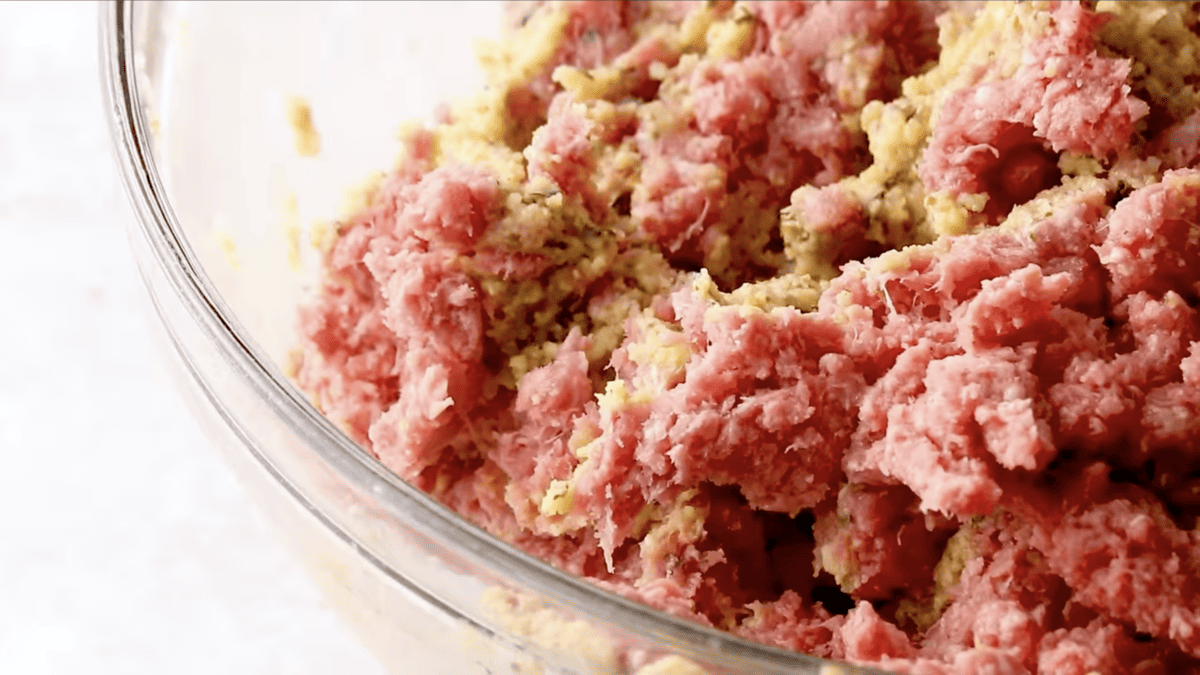 A bowl of homemade ground meat in a glass bowl, ready to be transformed into delicious meatballs.