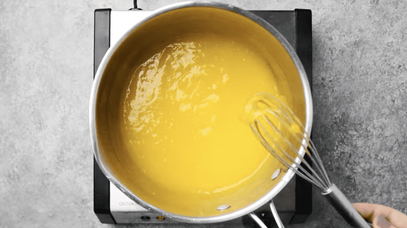 thick lemon curd in a saucepan with a whisk.