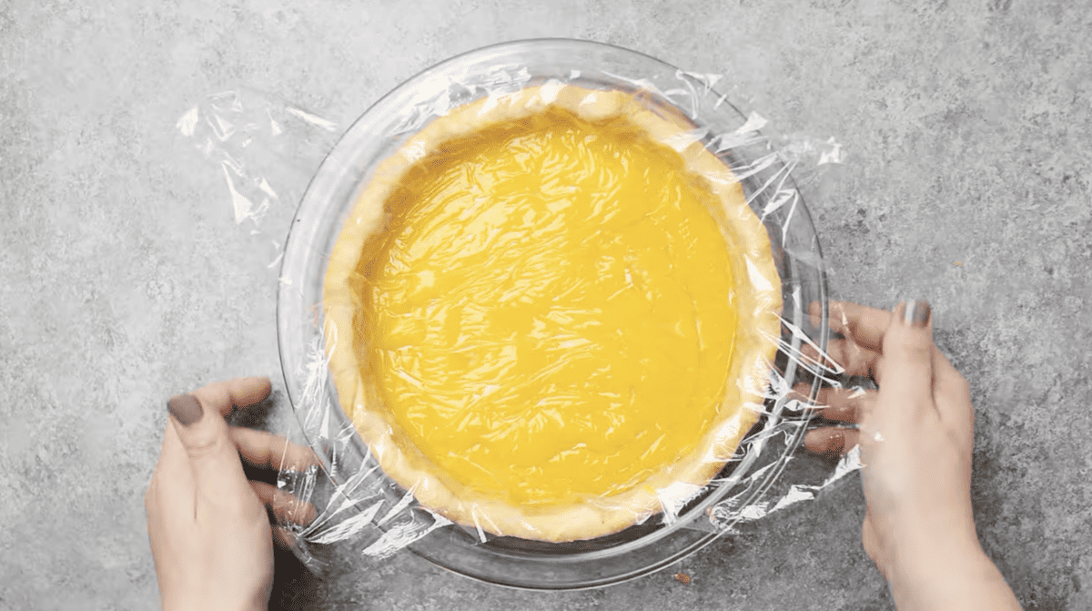 lemon curd in pie crust covered with plastic wrap.