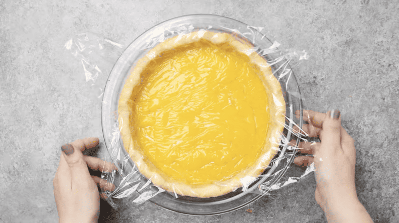 lemon curd in pie crust covered with plastic wrap.