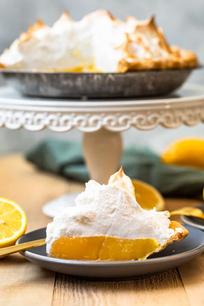 slice of lemon meringue pie next to whole pie on cake stand