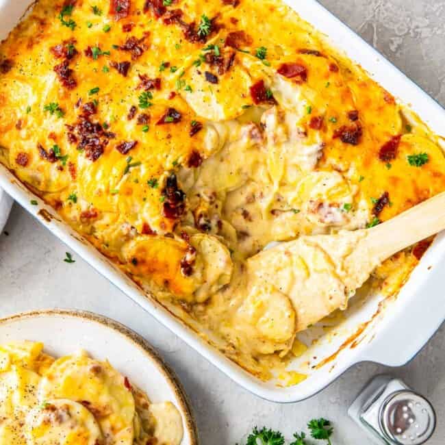 pan of loaded scalloped potatoes next to plate