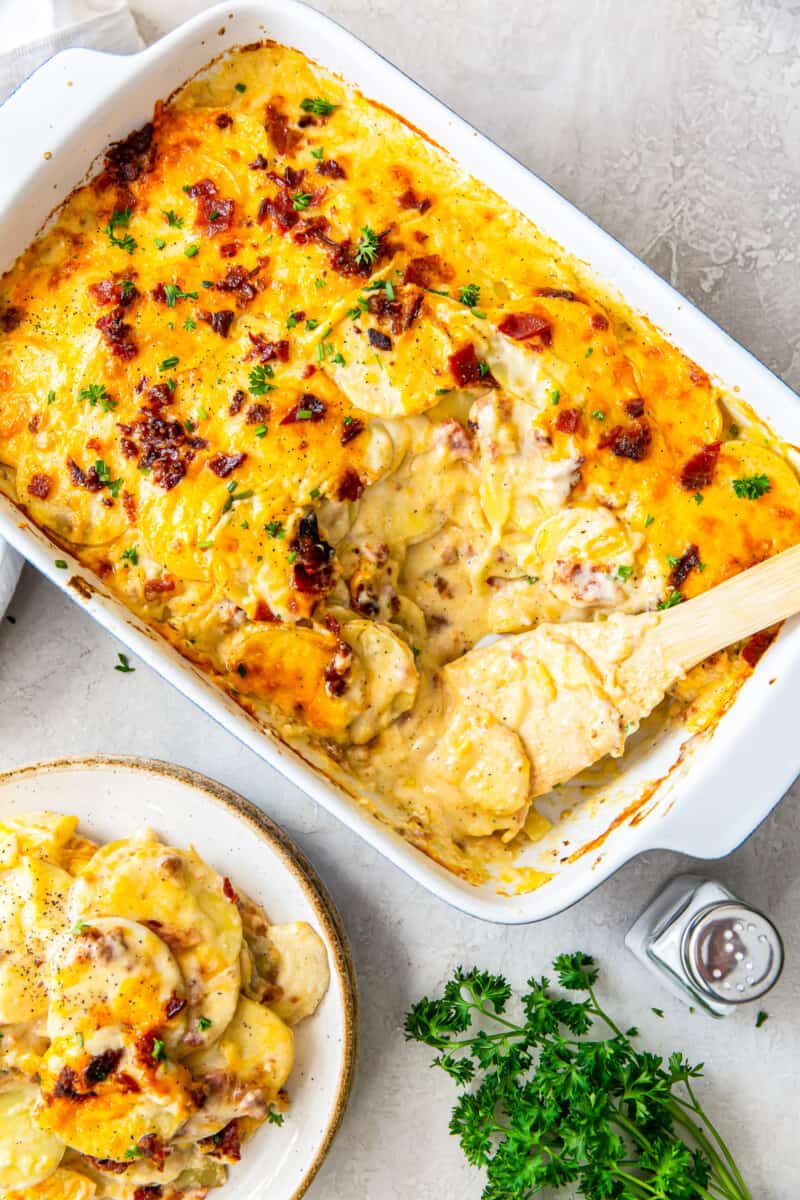 pan of loaded scalloped potatoes next to plate