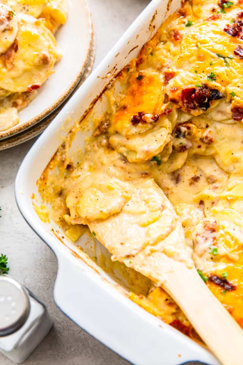 spoon in pan of loaded scalloped potatoes