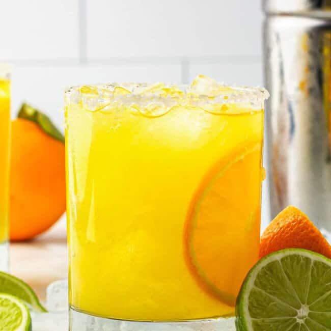 orange margarita next to cocktail shaker