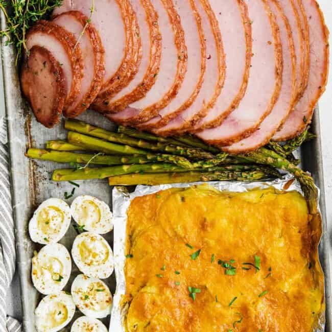 sheet pan easter dinner with ham, scalloped potatoes, hard boiled eggs, and asparagus