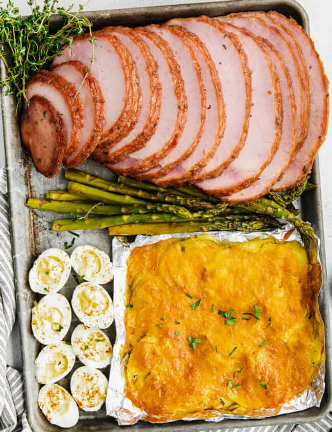 sheet pan easter dinner with ham, scalloped potatoes, hard boiled eggs, and asparagus