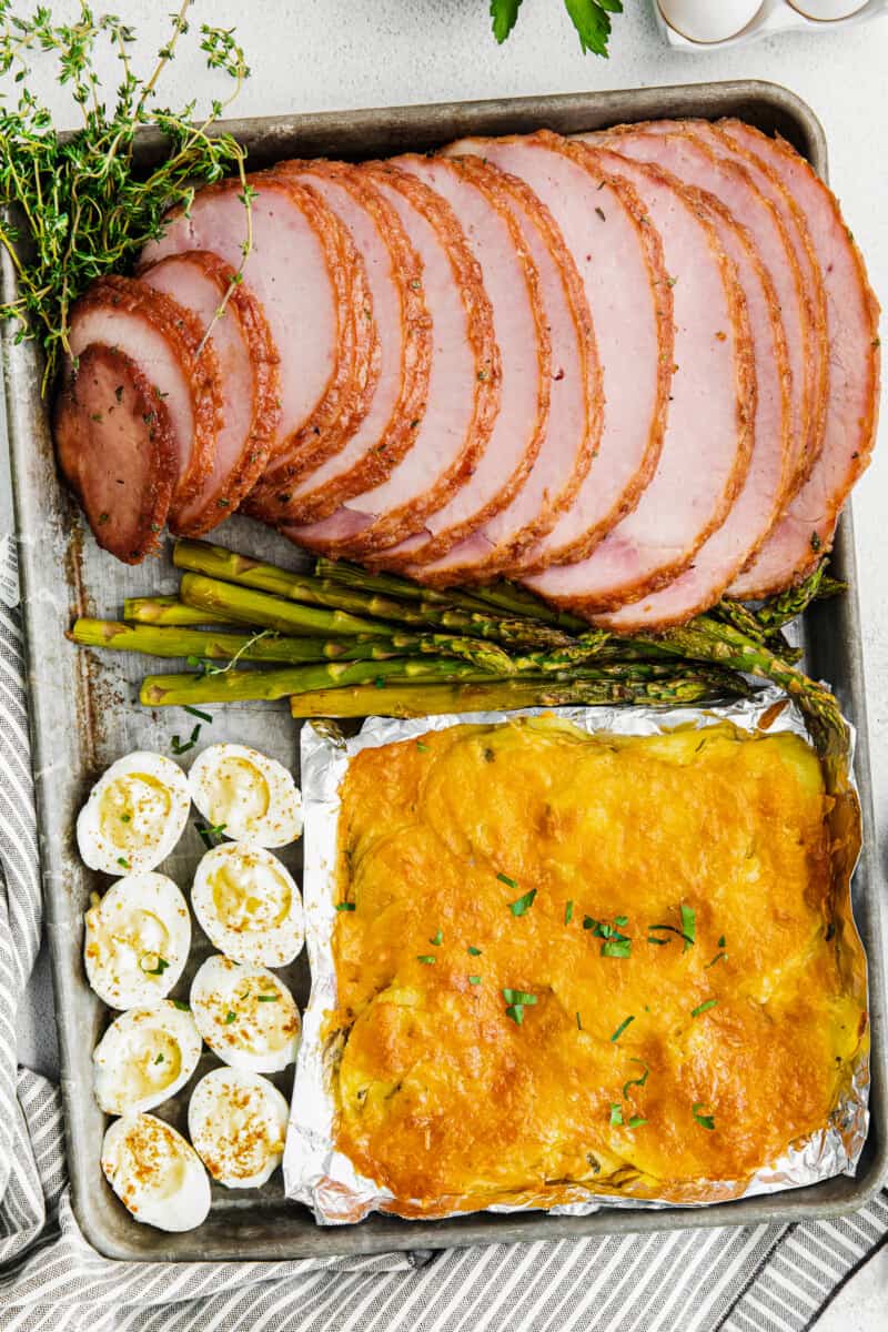 sheet pan easter dinner with ham, scalloped potatoes, hard boiled eggs, and asparagus