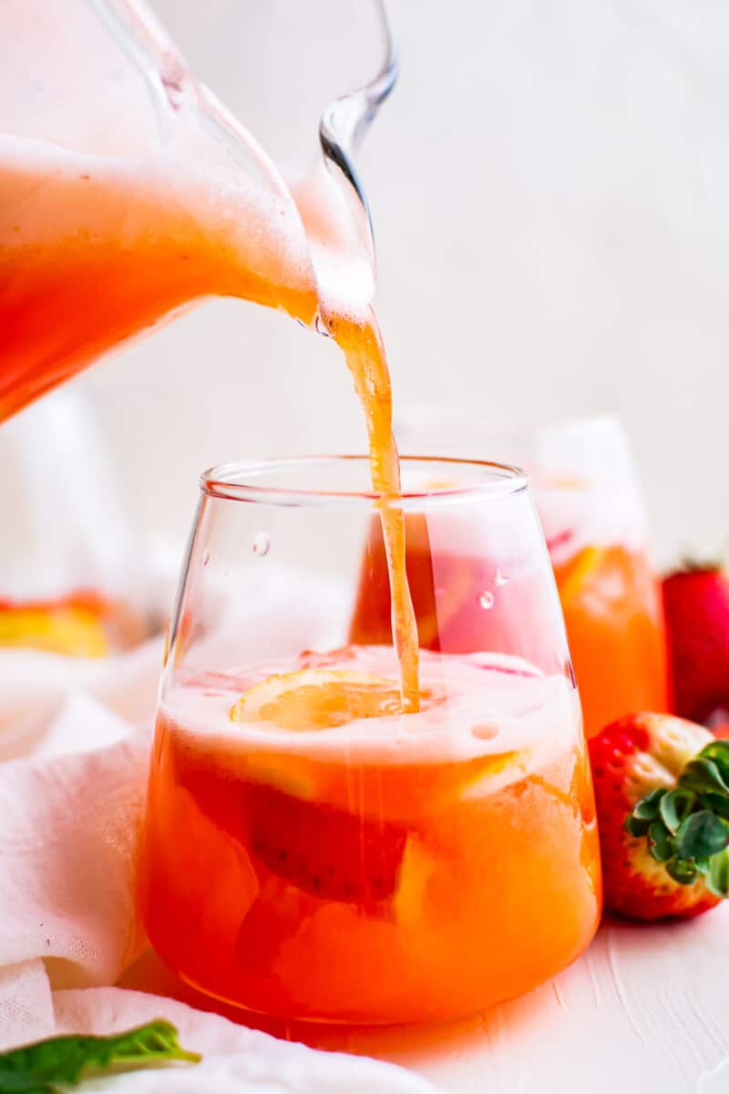 pouring strawberry lemonade into glass