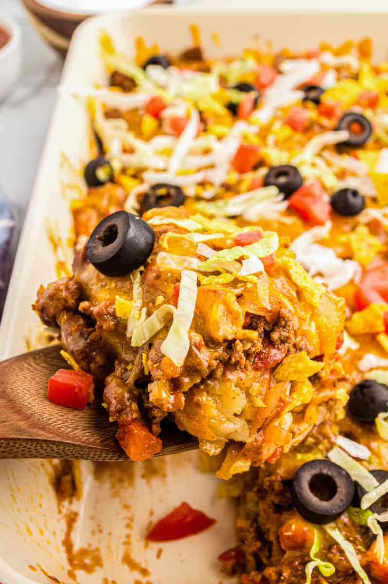 lifting up taco casserole in baking dish