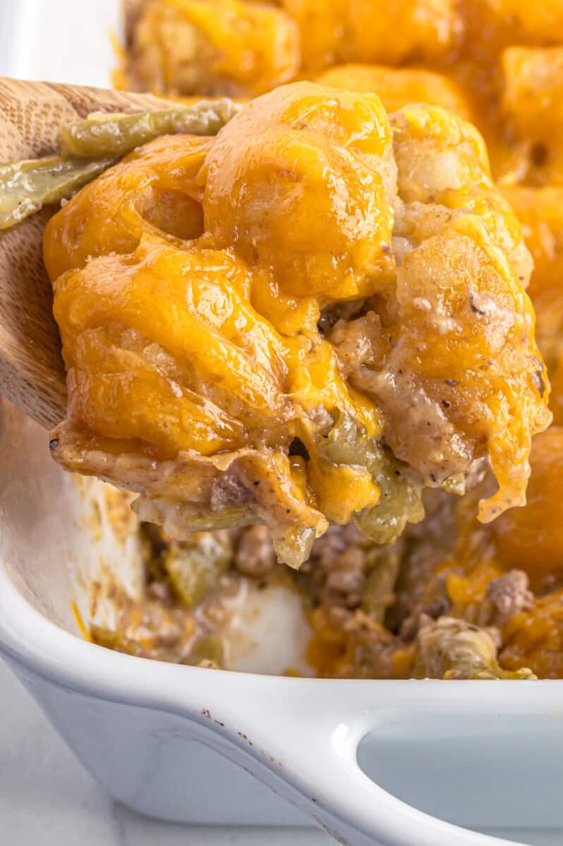 lifting up wooden spoon with tater tot casserole
