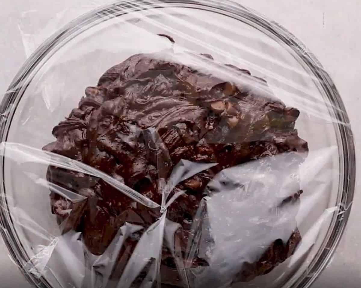 Brownie cookie batter in a glass bowl covered with plastic wrap.  - 7