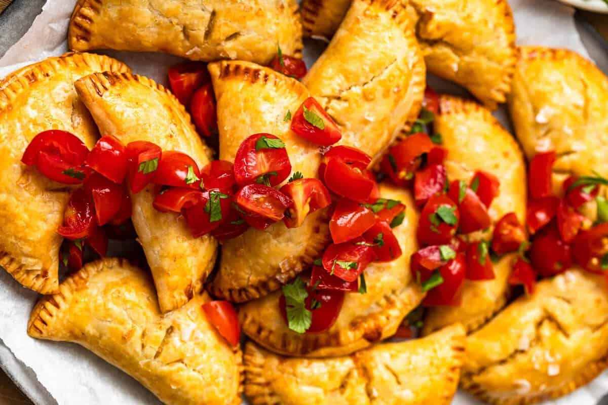 finished baked empanadas topped with tomatoes