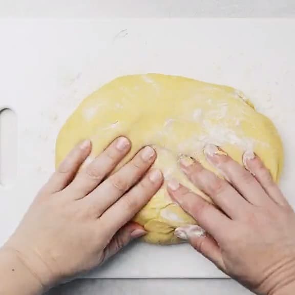 a person's hands are putting dough on a cutting board.