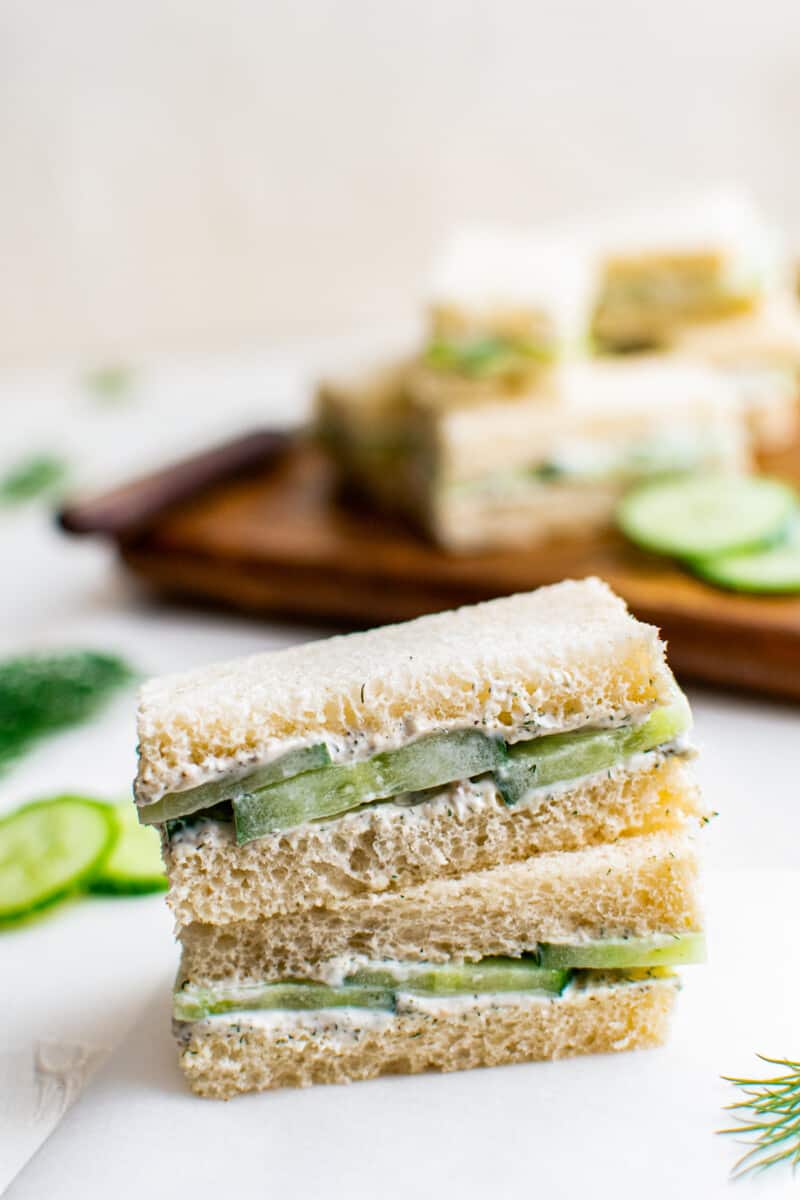 two stacked cucumber sandwiches on white table