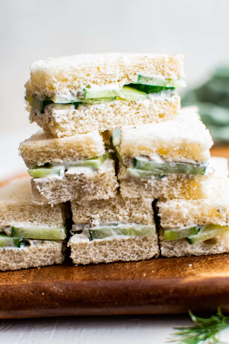 stacked cucumber sandwich slices on cutting board