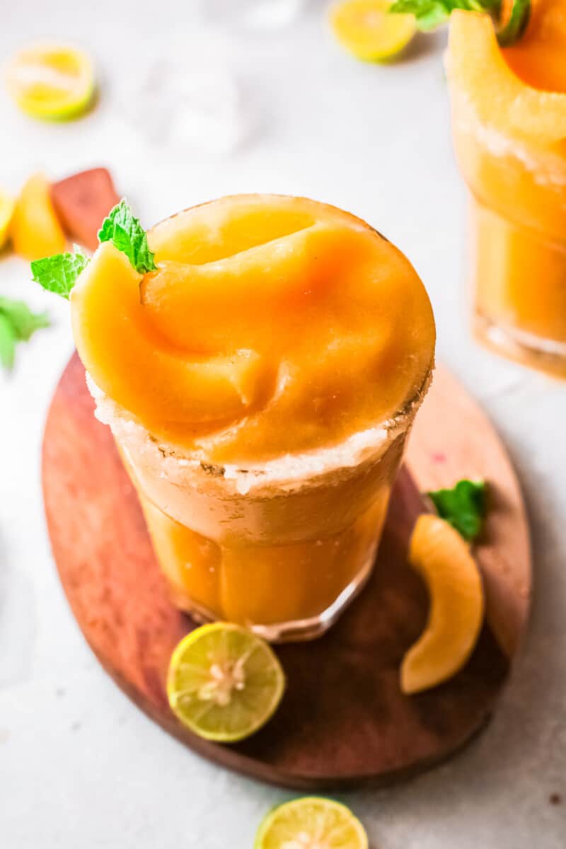 salt rimmed glass with frozen peach margarita