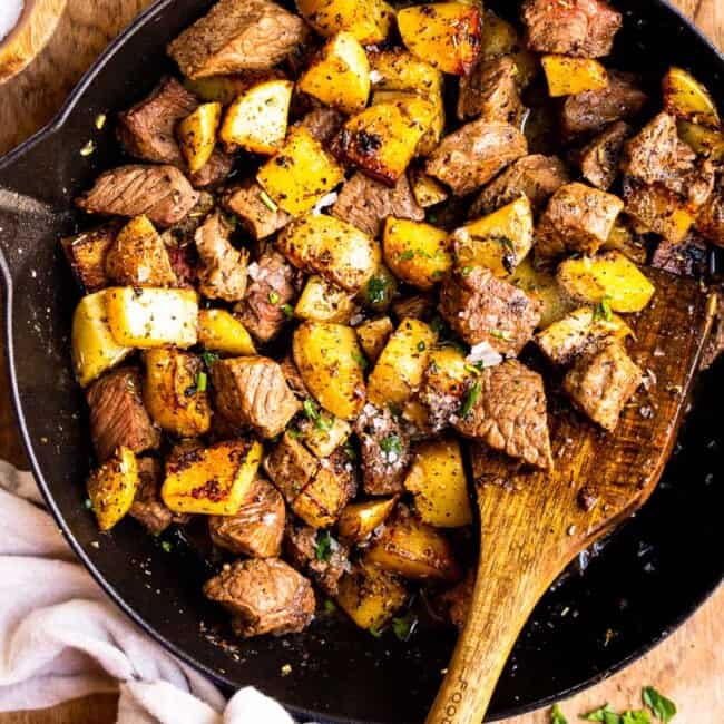 garlic butter steak bites with potatoes in skillet