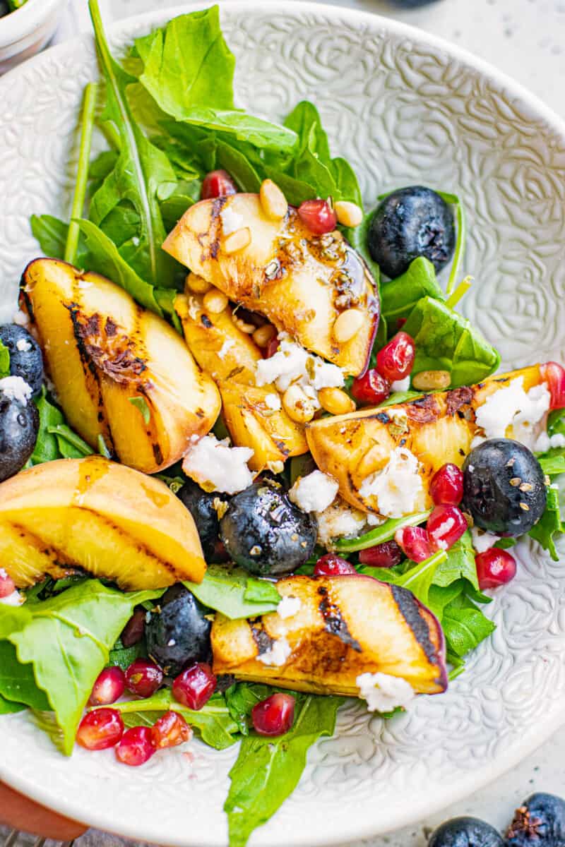 up close grilled peach salad with feta in bowl