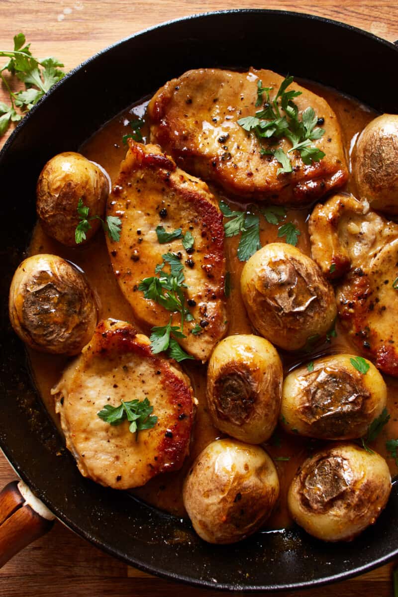 overhead view of honey mustard pork chops and potatoes in a skillet.