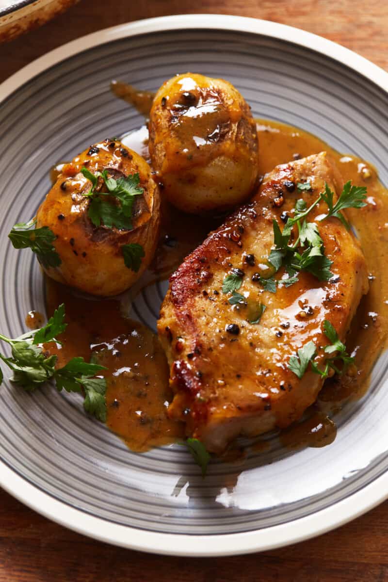 honey mustard pork chop on a gray plate with potatoes.