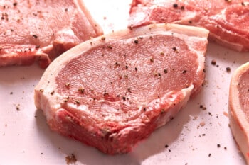 raw pork chops on a cutting board.