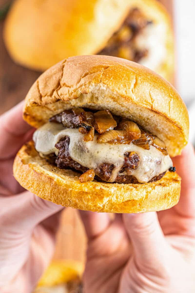 holding up grilled onion swiss burger