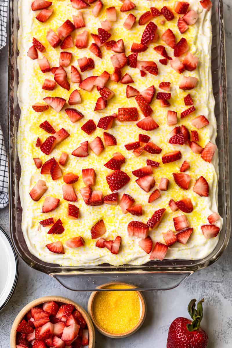 overhead strawberry lemonade poke cake garnished with fresh strawberries