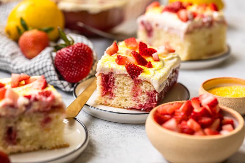 slices of strawberry lemonade poke cake on white plates