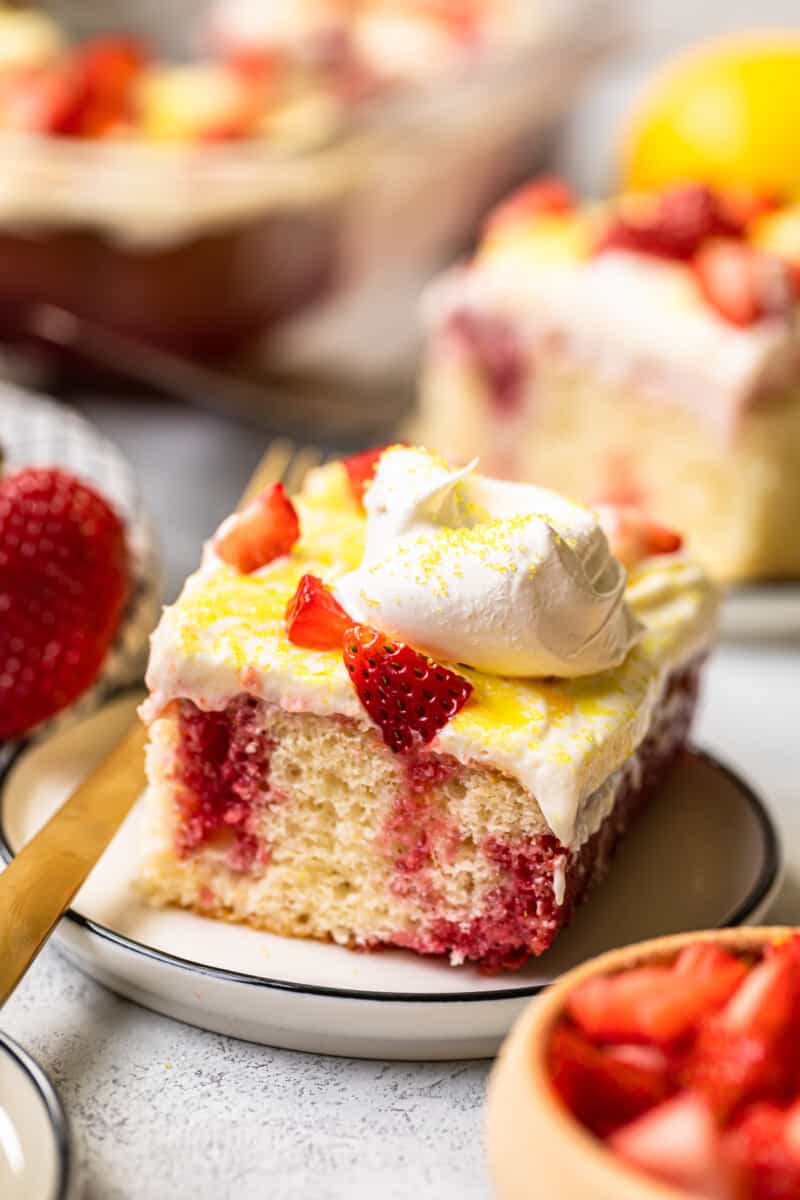 slices of strawberry lemonade poke cake on white plates