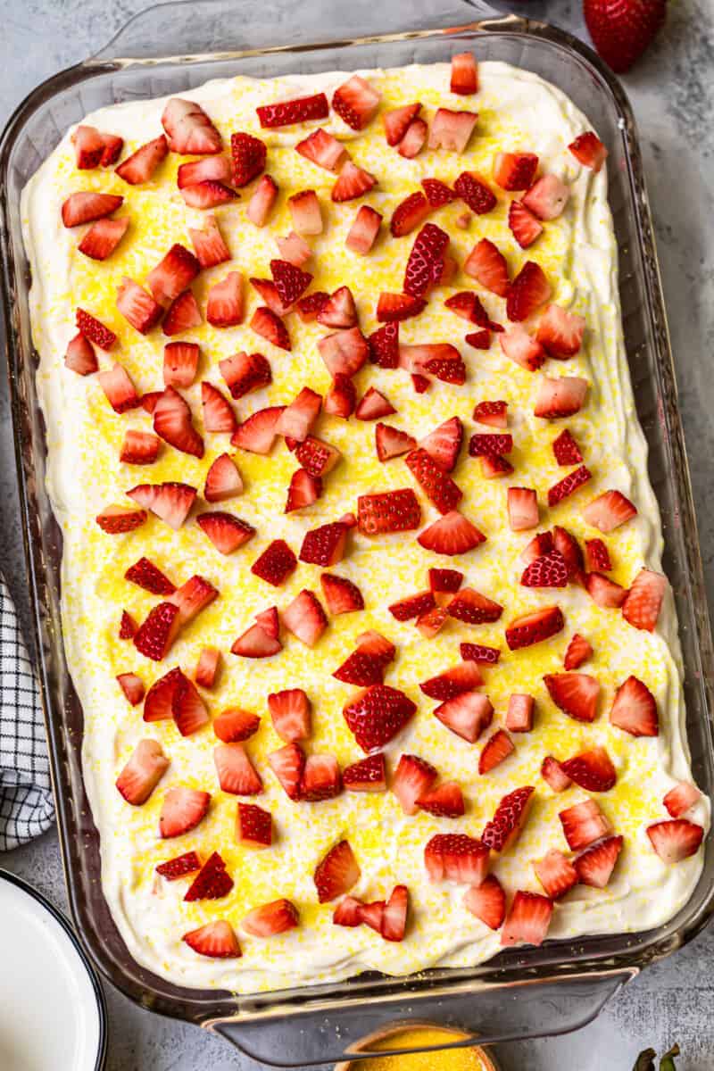 overhead strawberry lemonade poke cake garnished with fresh strawberries