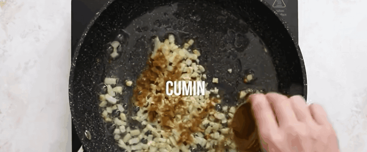 Cooking onions and seasonings in a black cast iron pan.