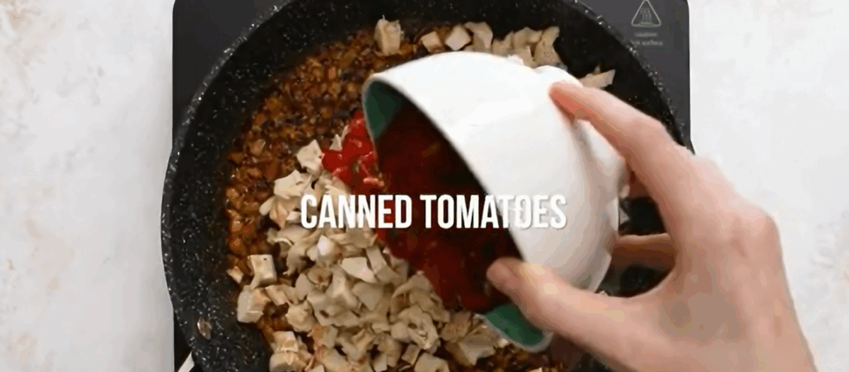 Add cooked chicken and canned tomatoes to the pan.