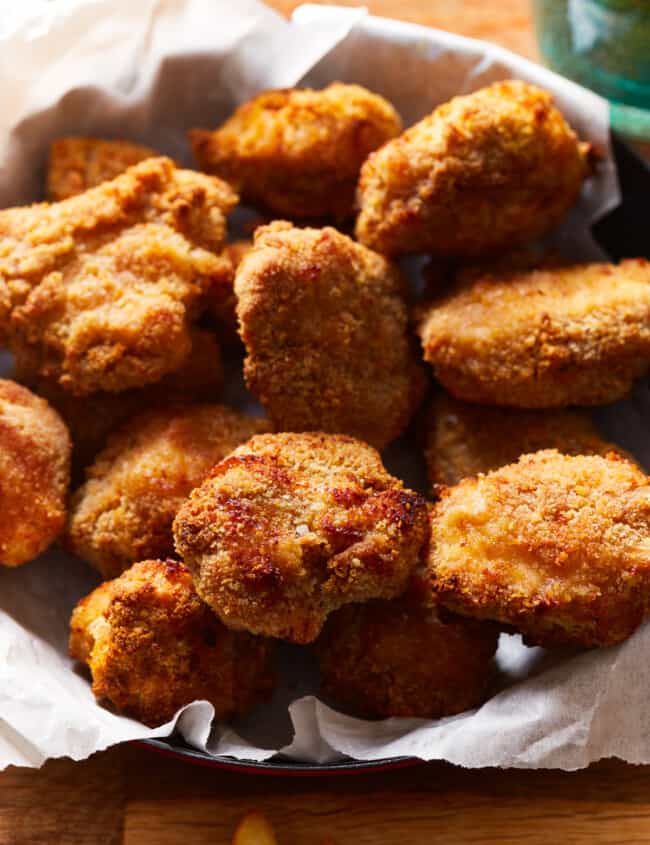 air fryer chicken nuggets in a parchment lined basket.