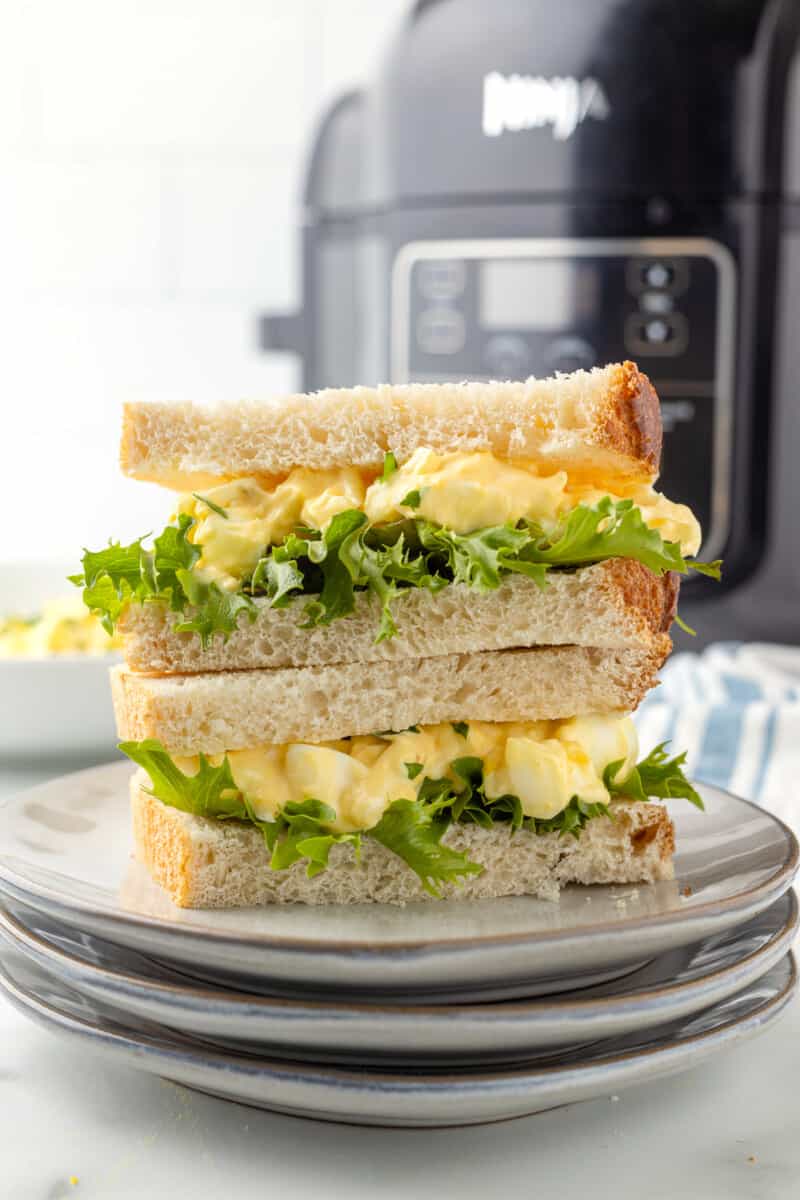 air fryer egg salad sandwiches stacked in front of air fryer