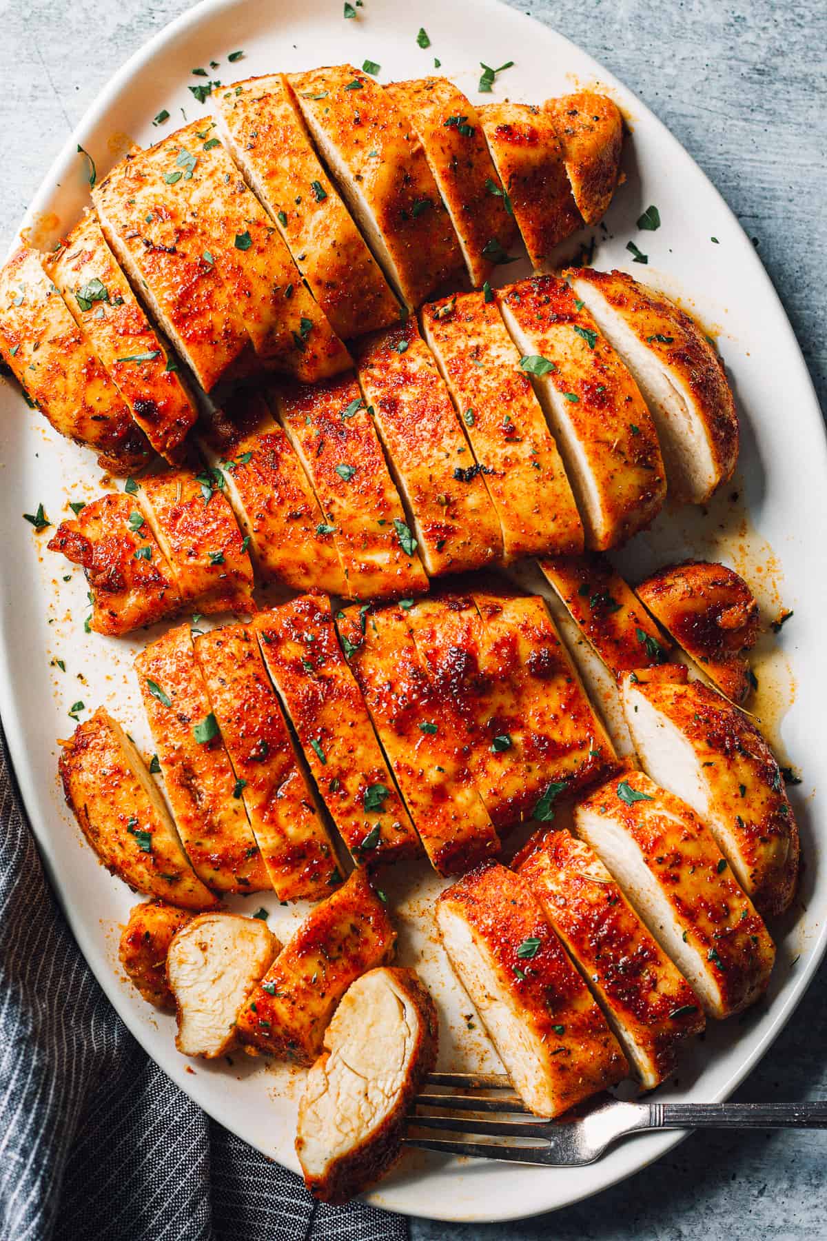 baked chicken breasts sliced on white platter
