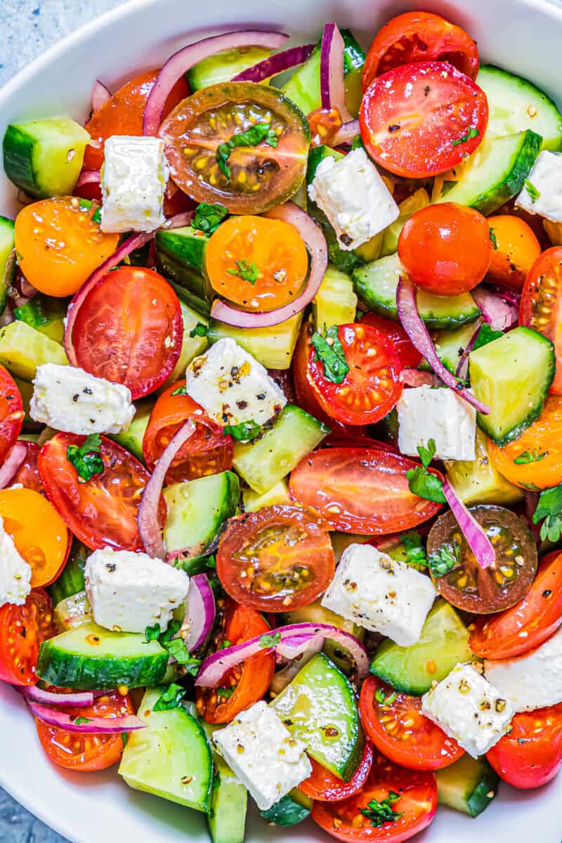 up close cucumber tomato salad in bowl with feta