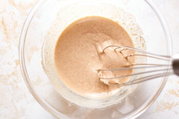 batter mixture for air fryer chicken nuggets in a glass bowl with a whisk.