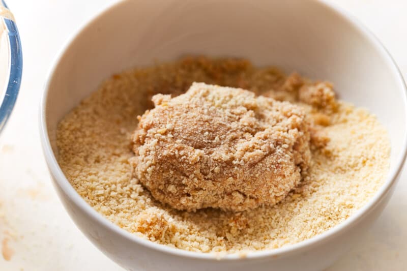 a chicken nugget dipped in breadcrumbs in a white bowl.
