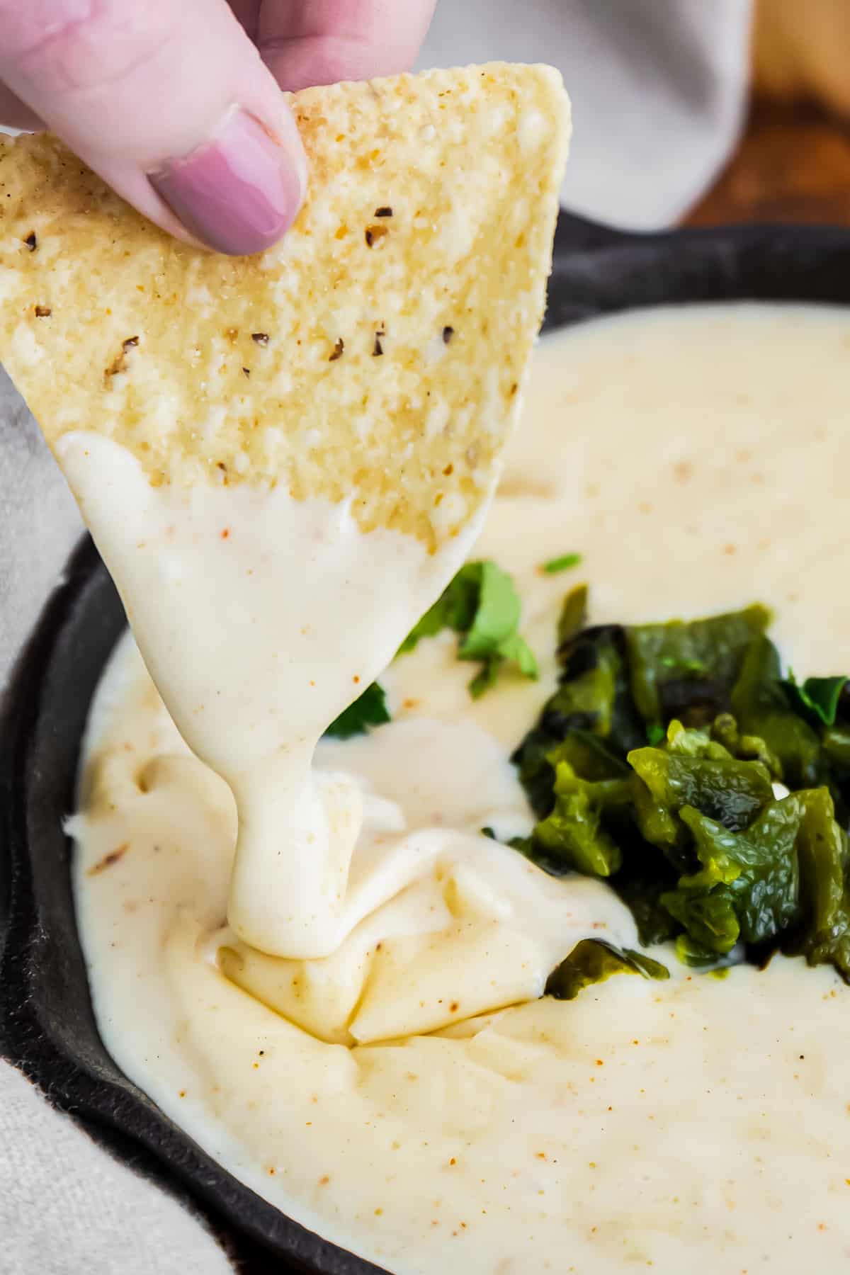 up close dipping chip in poblano queso