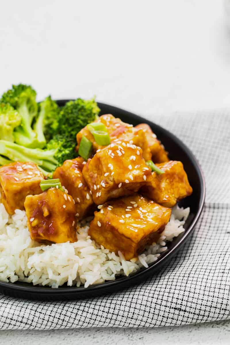 close up of air fryer teriyaki tofu on a black plate.