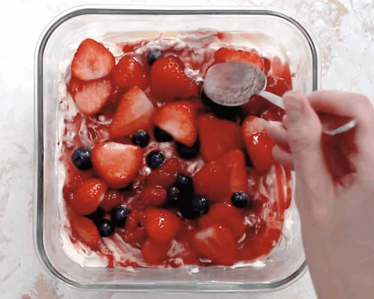 Layering the fruit over the cheese in a glass pan.