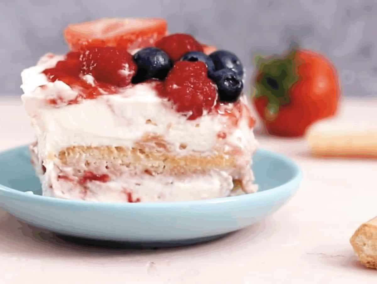 A slice of triple berry tiramisu in a shallow bowl.