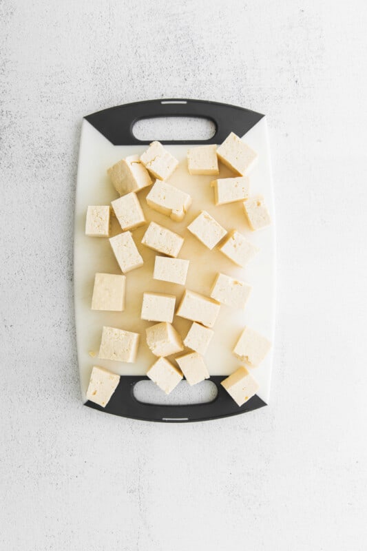 cubes of tofu for air fryer teriyaki tofu on a plastic cutting board.